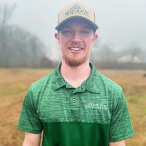 Photo Hunter Childers, Senior Technician for Deep South Construction Pros standing in a field wearing a green branded T-shirt.
