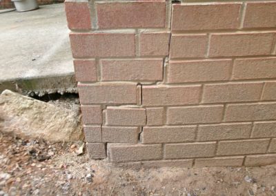 Cracks in the base of a brick wall caused by shifting foundation