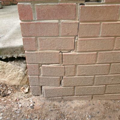Cracks in the base of a brick wall caused by shifting foundation