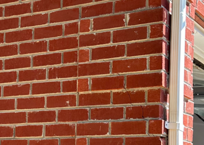 Cracks forming along the corner of a brick wall, showing foundation instability